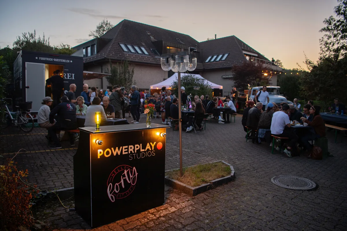 Menschen auf Festbänken. Die Powerplay Studios feiern ihr 40-Jahr-Jubiläum.